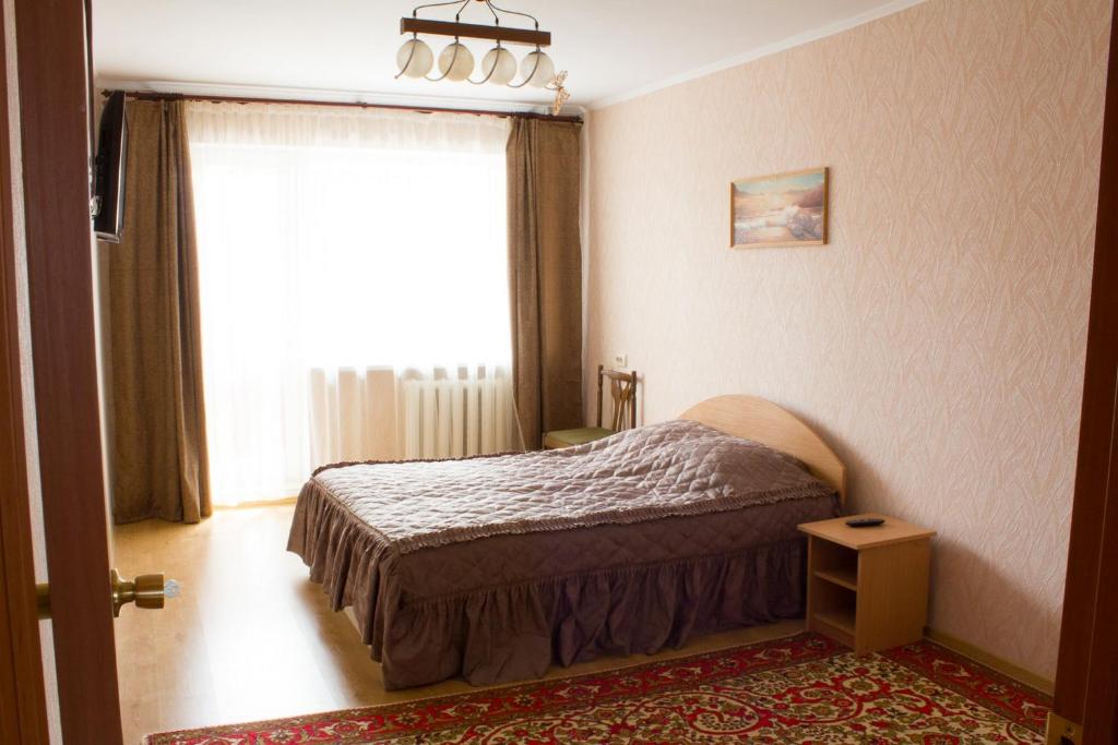 a bedroom with a bed and a large window at Ferrari Apartments in Vinnytsya