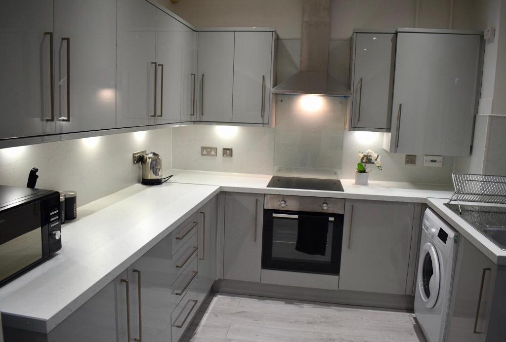 a kitchen with white counters and white cabinets at Kelpies Serviced Apartments- Russell in Falkirk