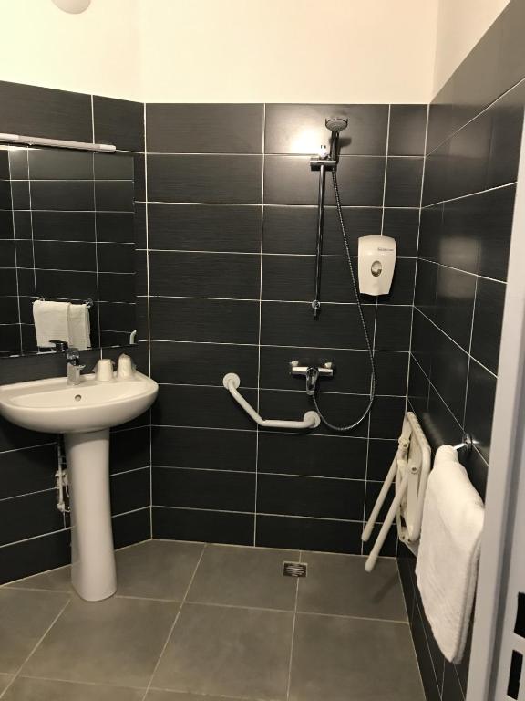 a black tiled bathroom with a sink and a shower at Première Classe Reims Ouest - Tinqueux in Reims