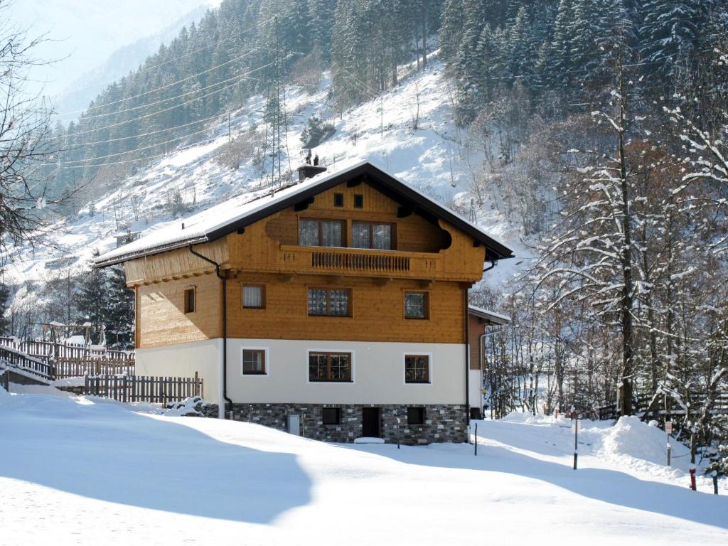 een houten huis in de sneeuw met een berg bij Apartment Schragl - MHO487 by Interhome in Ginzling
