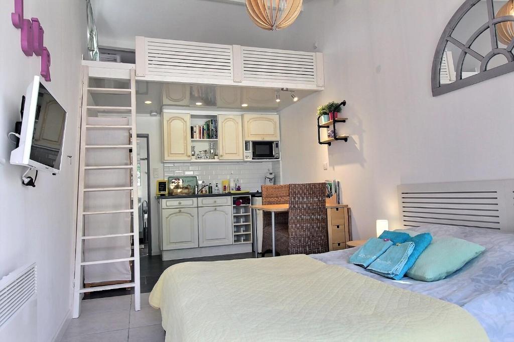 een kleine slaapkamer met een bed en een keuken bij Le Petit Paradis - La Provençale in Lorgues