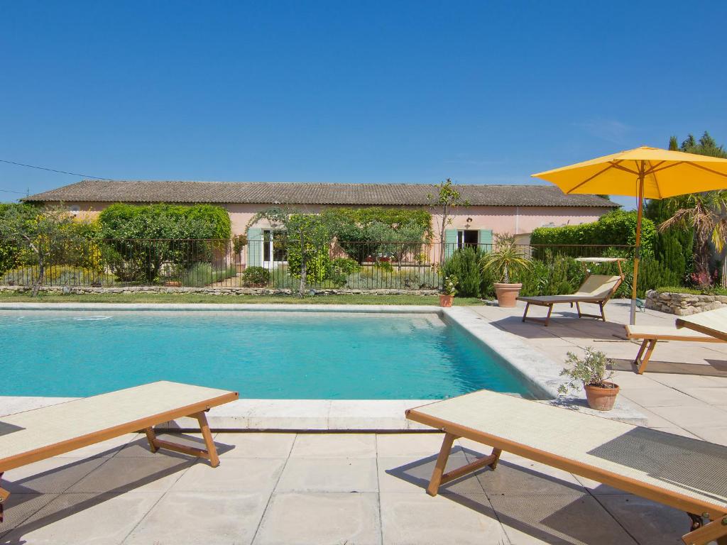 a swimming pool with two picnic tables and an umbrella at Holiday Home L'Olivier by Interhome in Lagnes