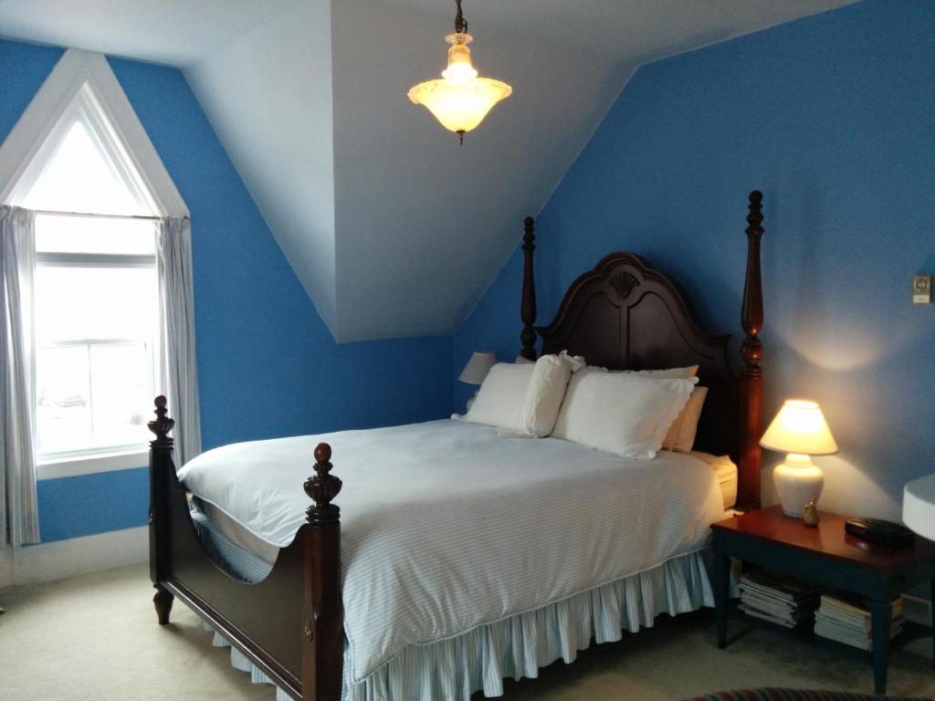 - une chambre avec un lit aux murs bleus et une fenêtre dans l'établissement Fairmont House Bed & Breakfast, à Mahone Bay