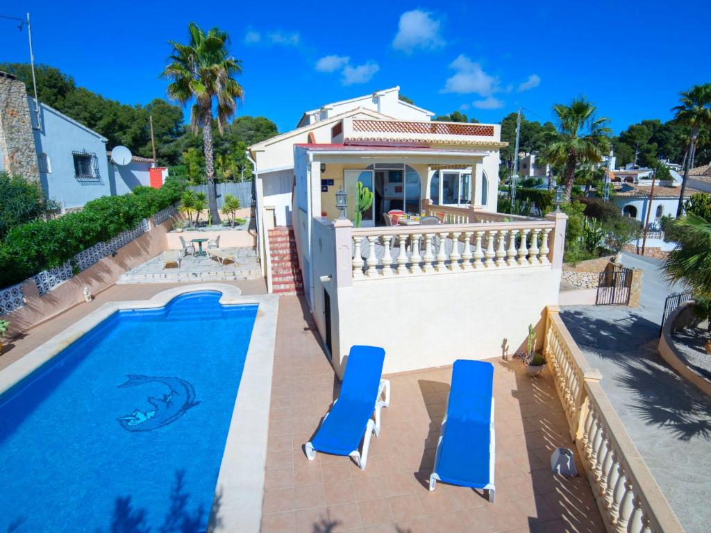 a house with a swimming pool and two blue chairs at Holiday Home Meluca by Interhome in Calpe