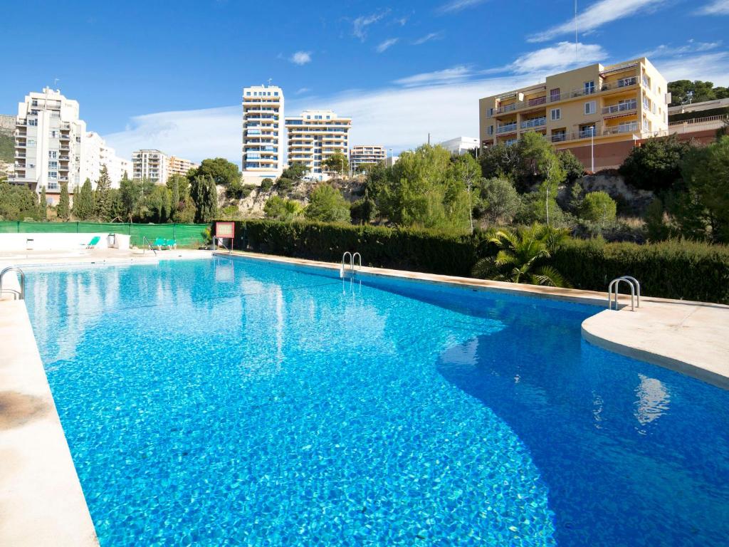 una grande piscina blu con edifici sullo sfondo di Apartment Zeus by Interhome a Calpe