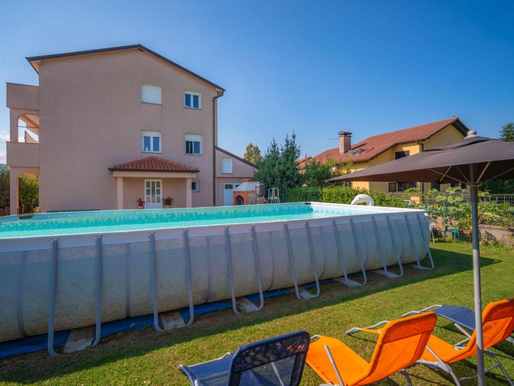 a pool in front of a house with chairs and an umbrella at Apartment Rita by Interhome in Dražice