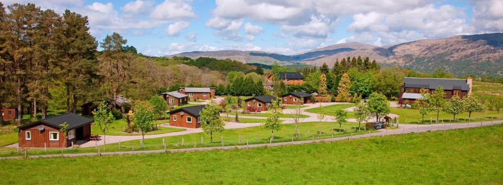 un groupe de maisons dans un champ avec des montagnes en arrière-plan dans l'établissement Airdeny Chalets, à Taynuilt