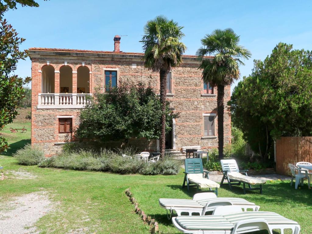 a building with chairs and palm trees in the yard at Holiday Home Podere Casina by Interhome in Sinalunga