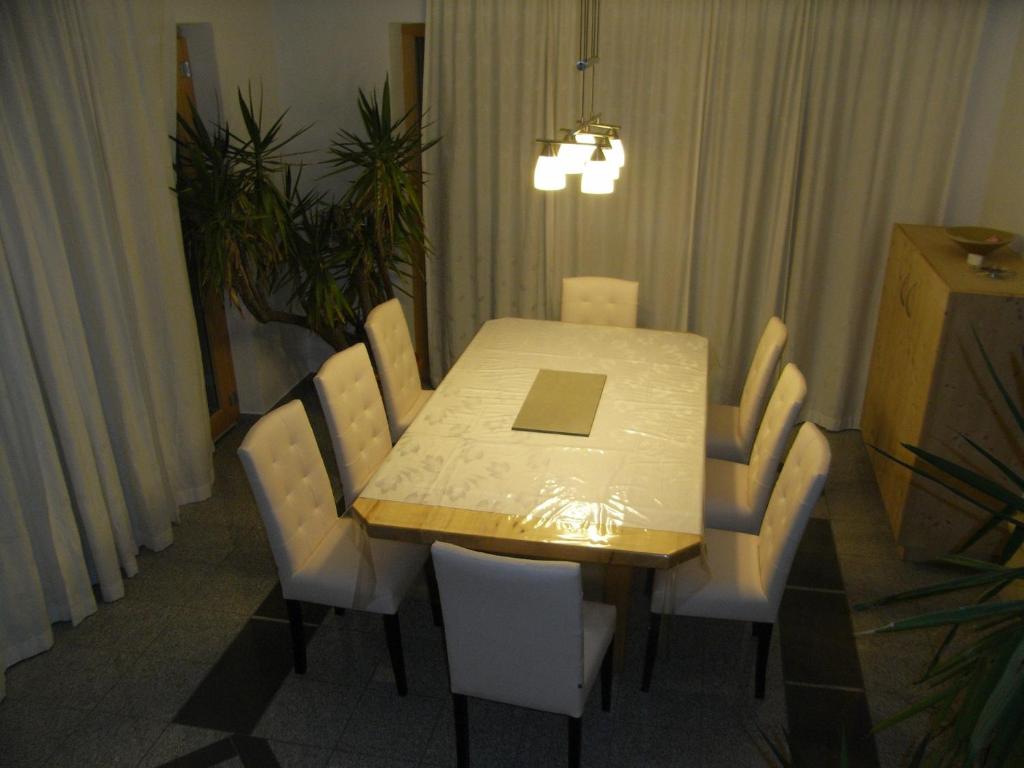 a dining room table with white chairs and a laptop on it at Apartment-Bergblick in Aschau
