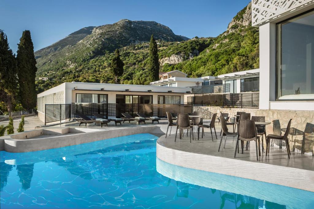 a house with a pool and chairs and a mountain at Erolidae Villas in Atsoupádhes