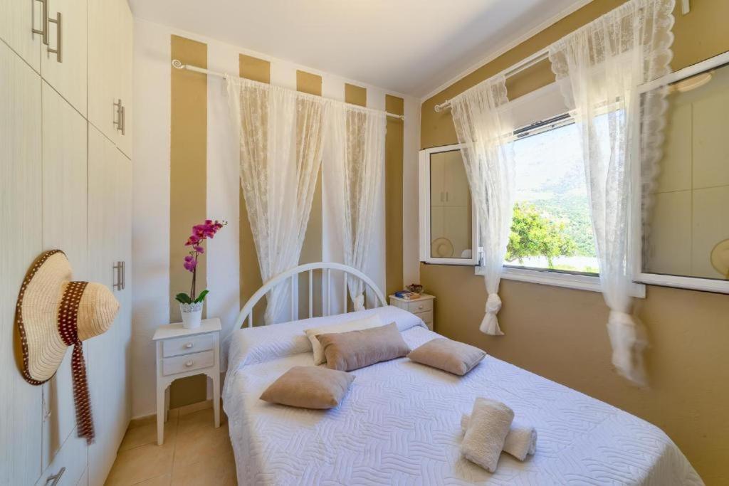 1 dormitorio con 1 cama con 2 almohadas y ventana en Emmanuela House with garden & sea view - Triopetra, en Triopetra