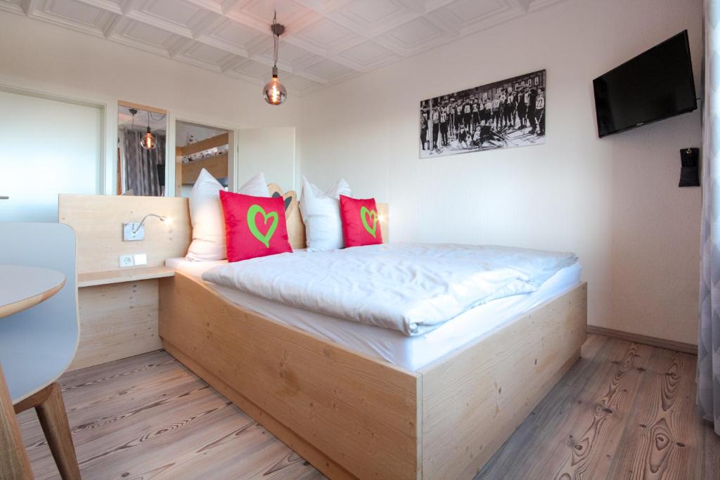 sypialnia z drewnianym łóżkiem i różowymi poduszkami w obiekcie Haus am Berg - Pension direkt am Skihang w mieście Kurort Oberwiesenthal