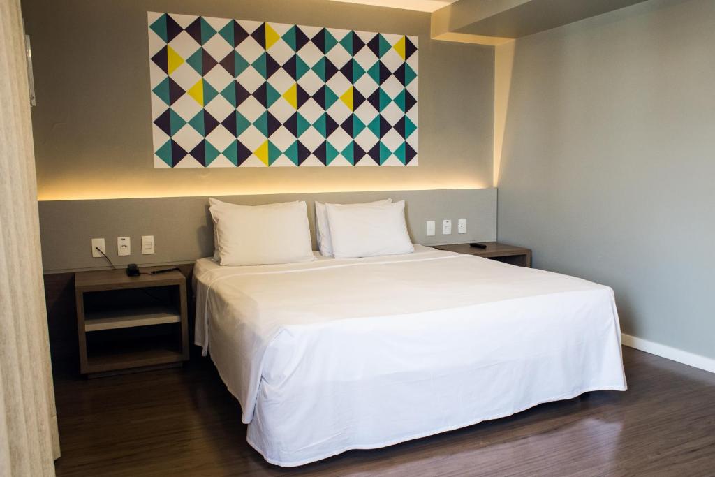 um quarto com uma cama branca e um quadro na parede em Master Express Cidade Baixa - Próximo à UFRGS e à Santa Casa em Porto Alegre