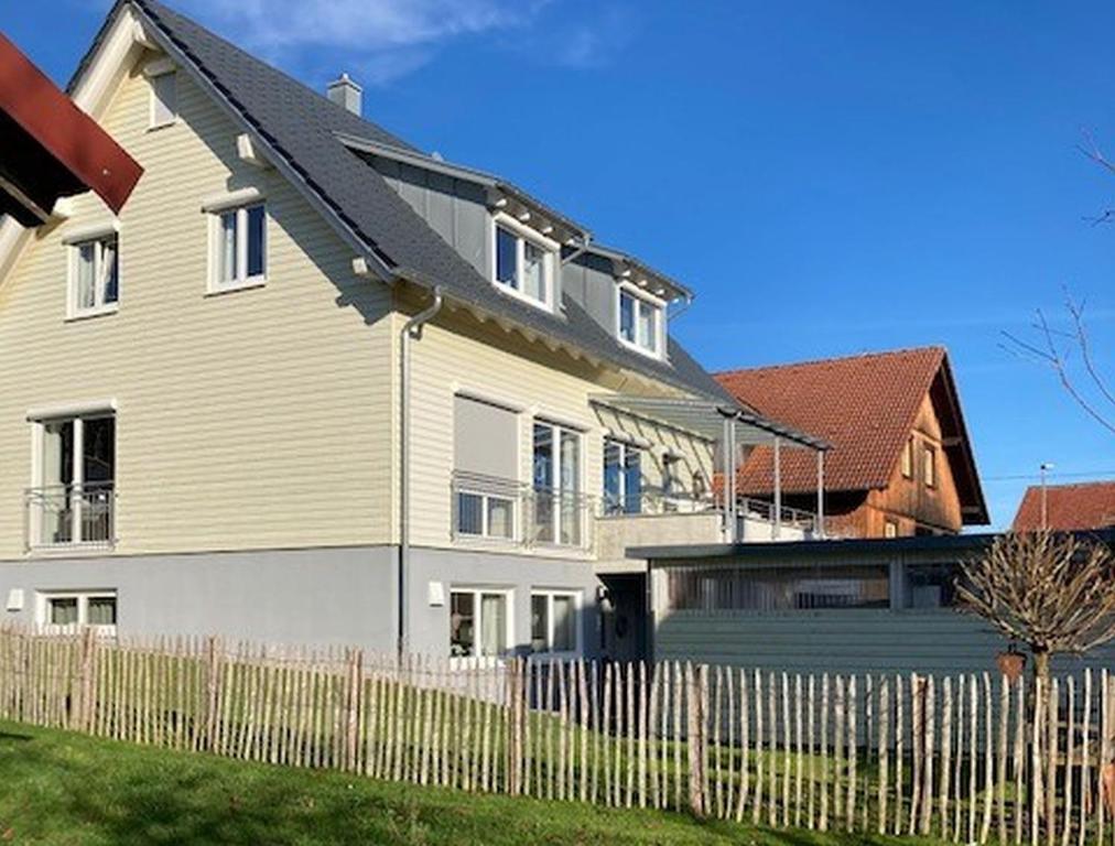 ein weißes Haus mit einem Zaun davor in der Unterkunft Ferienwohnung Familie Igel in Horgenzell