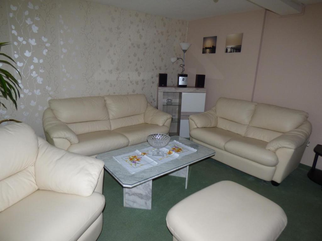 a living room with two white couches and a coffee table at Werner's Gästewohnung in Kraftsdorf