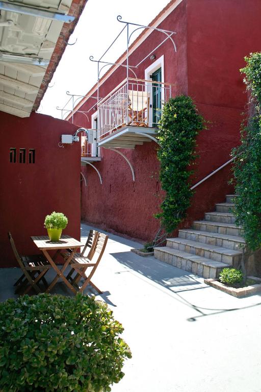 a red building with stairs and a table and chairs at Zefiros Traditional Hotel in Paleokastritsa
