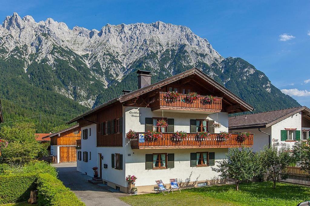 a building with a balcony with chairs and mountains at Landhaus Braun in Mittenwald