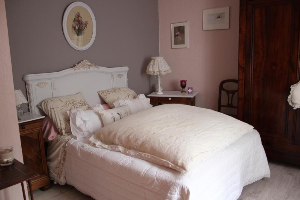 a bedroom with a white bed with white sheets and pillows at petite maison berrichonne in Chârost