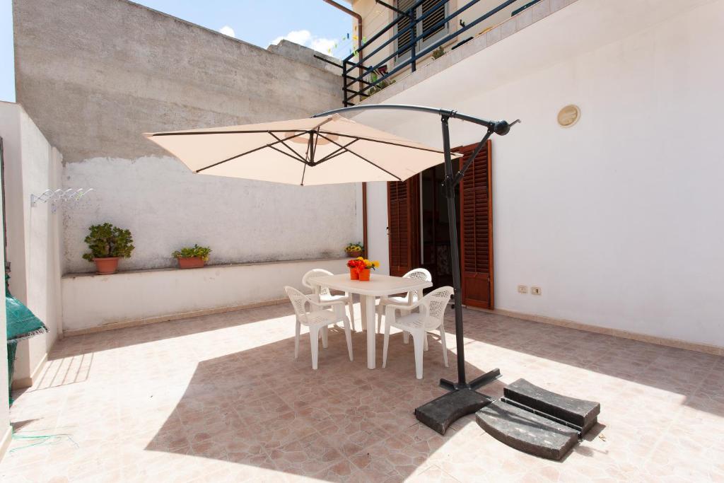 a white table with chairs and an umbrella on a patio at Casa Viga in Tre Fontane