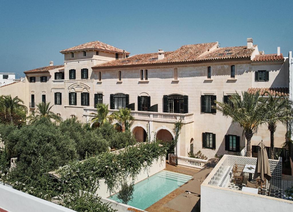 une grande maison avec une piscine en face de celle-ci dans l'établissement Faustino Gran Relais & Chateaux, à Ciutadella