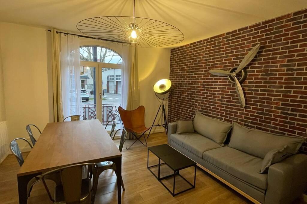 - un salon avec un canapé et un mur en briques dans l'établissement L'historique - Au Cœur de Verdun, à Verdun-sur-Meuse