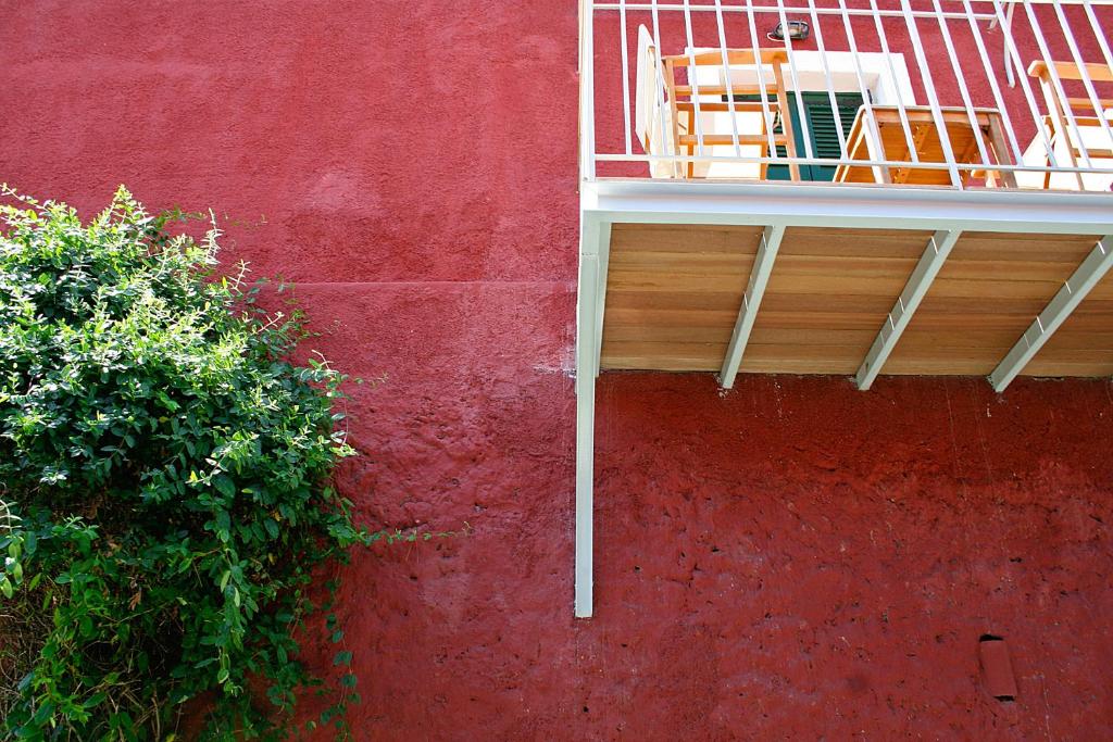 a red wall with a balcony with chairs on it at Zefiros Traditional Hotel in Paleokastritsa