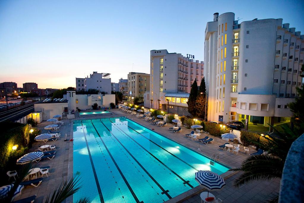 a swimming pool with chairs and umbrellas next to buildings at HR Senigallia, già Hotel Ritz in Senigallia