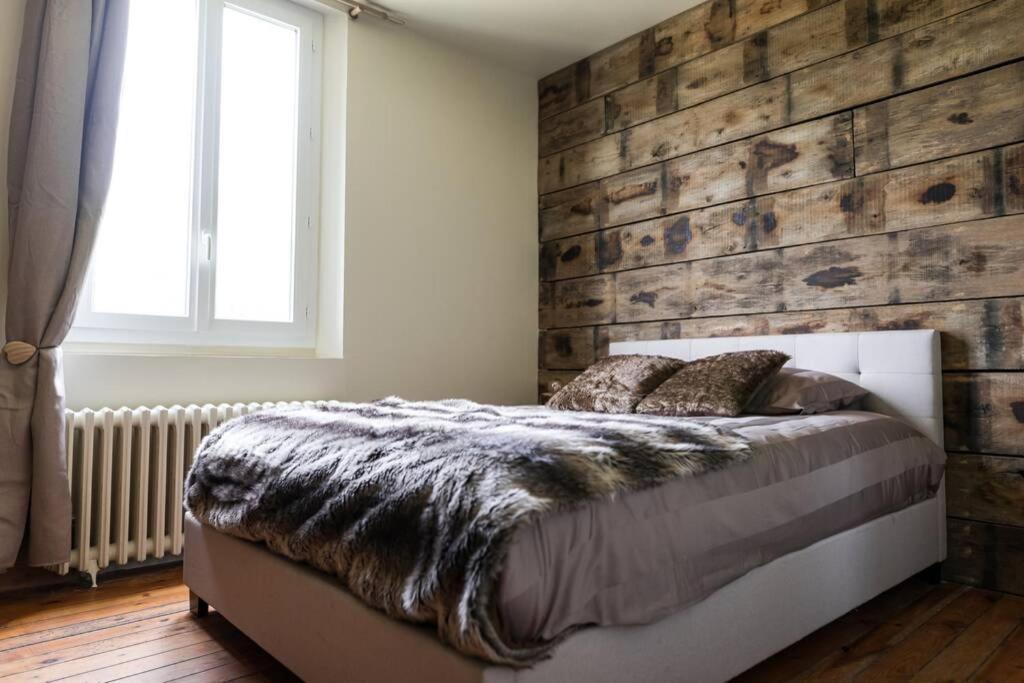 a bedroom with a bed with a wooden wall at La Villa de l&#39;Etoile jacuzzi privé chauffé à 37°C in Forges-les-Eaux