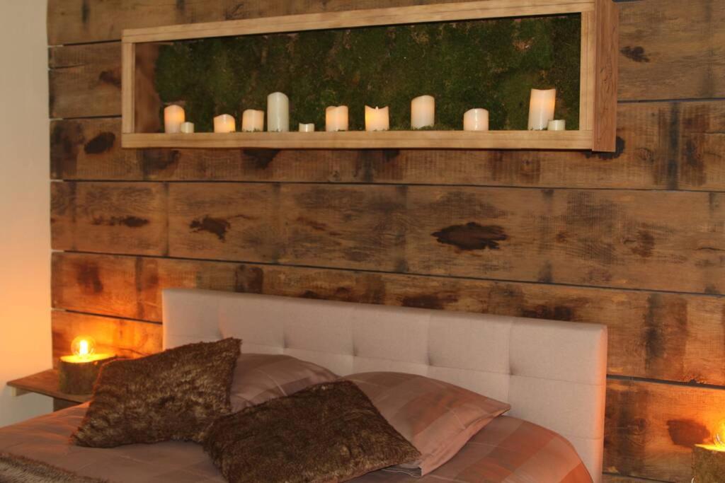 a bedroom with a wooden wall with a bed and candles at La Villa de l&#39;Etoile jacuzzi privé chauffé à 37°C in Forges-les-Eaux