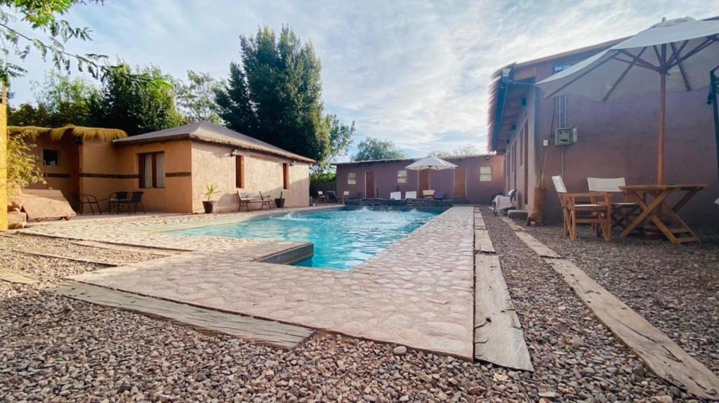 un patio trasero con piscina y una casa en Ickota B&B en San Pedro de Atacama