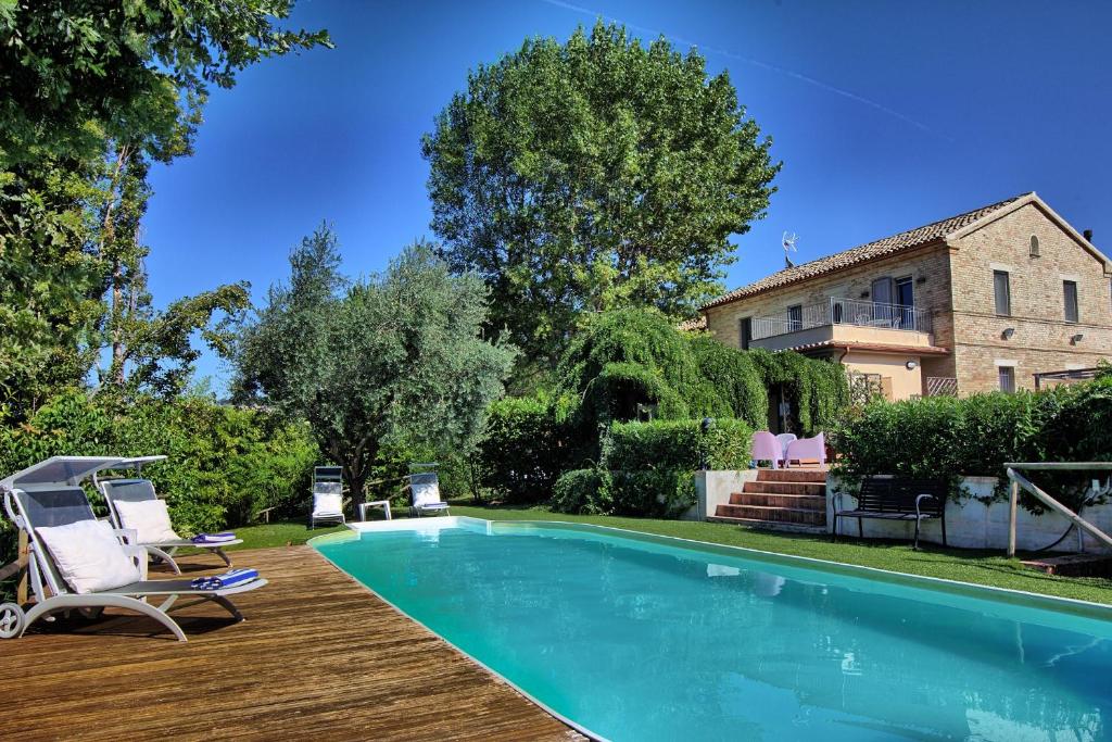 OstraにあるGrande villa storica per vacanze con giardino privato e piscinaのスイミングプール(椅子付)と家
