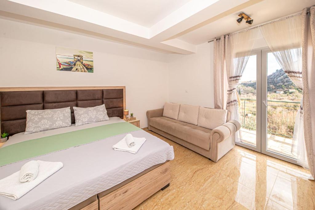 ein Schlafzimmer mit einem Bett, einem Sofa und einem Fenster in der Unterkunft Skadar lake Apartments Pajovic in Virpazar