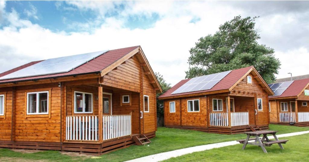 un grupo de casas de madera con paneles solares en Bacchus Hotel Log Cabins en Sutton on Sea