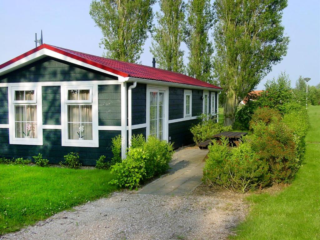 デン・ウフェルにあるHoliday Home De Wierde by Interhomeの赤屋根の小さな青い家