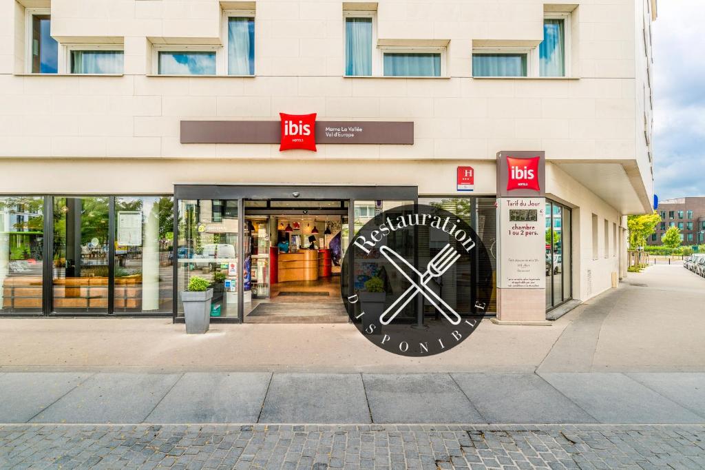 un magasin avec une grande horloge devant lui dans l'établissement ibis Marne La Vallée Val d'Europe, à Montévrain