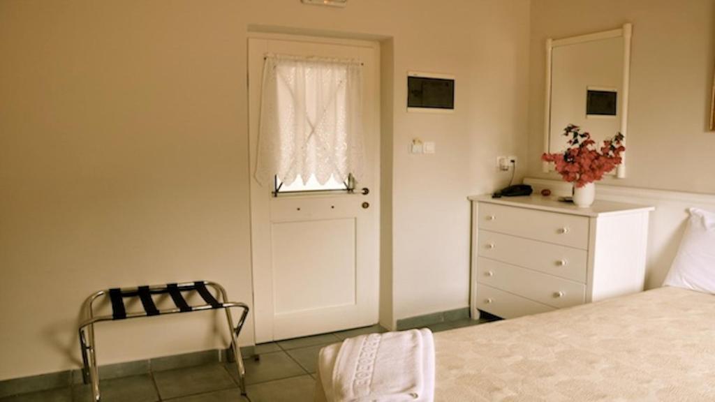 a bedroom with a bed and a window and a dresser at Zefiros Traditional Hotel in Paleokastritsa