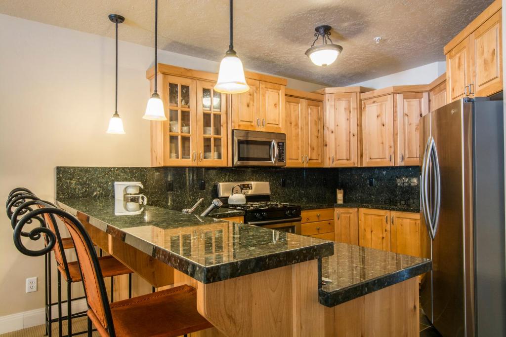 a kitchen with wooden cabinets and a stainless steel refrigerator at Town Point Condos by Lespri Property Management in Park City