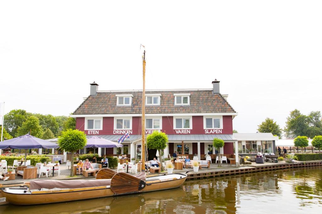 un grand bâtiment rouge avec des bateaux dans l'eau dans l'établissement Schippershuis Terherne, à Terherne