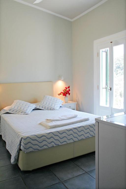a white bedroom with a bed and a window at Zefiros Traditional Hotel in Paleokastritsa