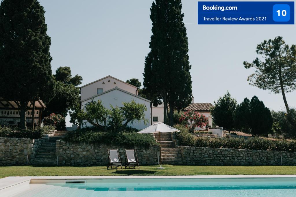 uma casa e uma piscina com duas cadeiras e um guarda-sol em L'Ulivo Bianco em Montenero di Bisaccia