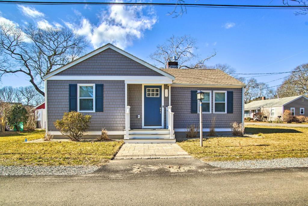 a small house with a blue door on a street at Updated Buzzards Bay Beach Cottage Walk to Shore! in Buzzards Bay