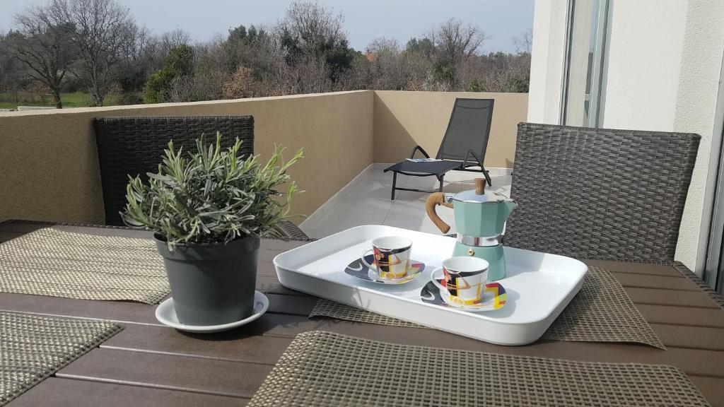 eine Kaffeemaschine und zwei Tassen auf einem Tisch auf einer Terrasse in der Unterkunft Apartment Janja in Medulin
