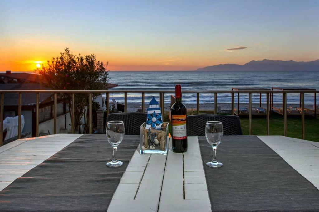 stół z butelką wina i dwoma kieliszkami w obiekcie Maistro Beach House w Acharavi