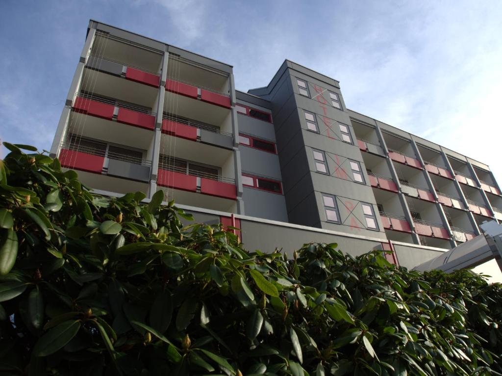 un edificio de apartamentos con ventanas rojas y un seto en Hotel im Park, en Bad Iburg
