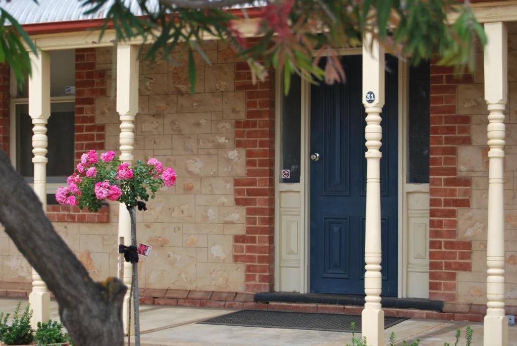 a blue door on a brick house with pink flowers at Jacaranda Cottage in Murray Bridge