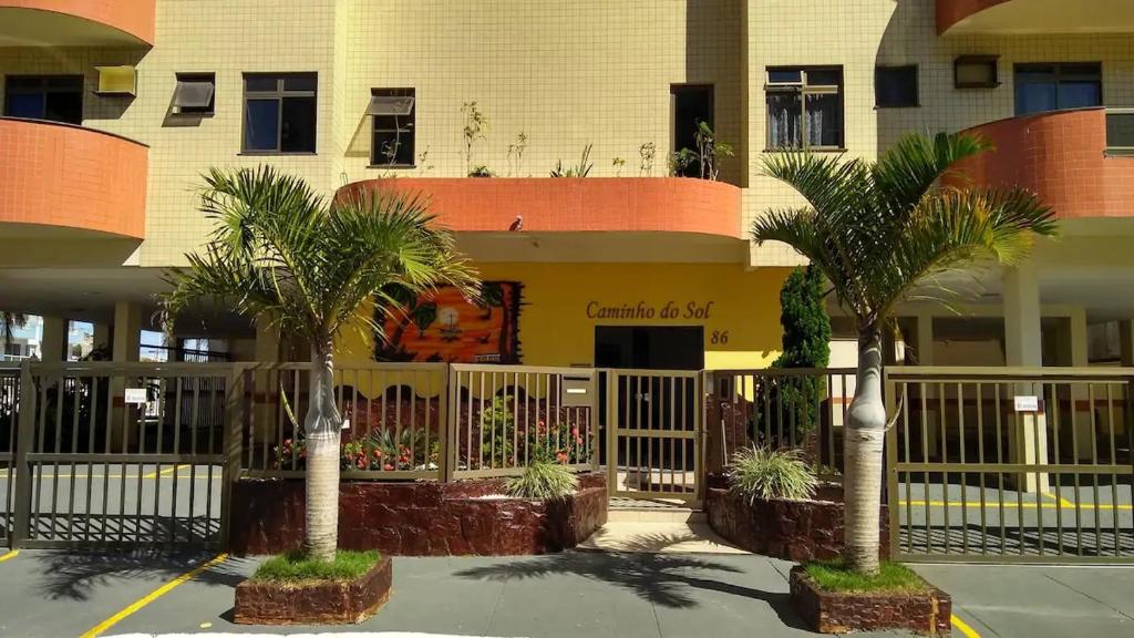 duas palmeiras em frente a um edifício em Apartamento na Prainha, de um quarto! em Arraial do Cabo