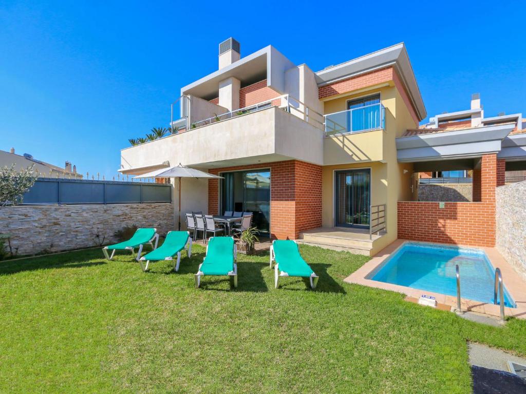 uma casa com um quintal com cadeiras e uma piscina em V3, Villa Jardins Branqueira6 near Beach, Albufeira em Albufeira