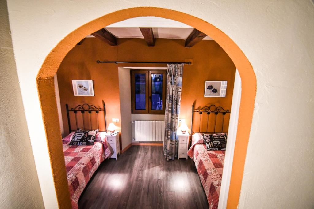 two beds in a room with an arched doorway at aCienLeguas in Castrojeriz