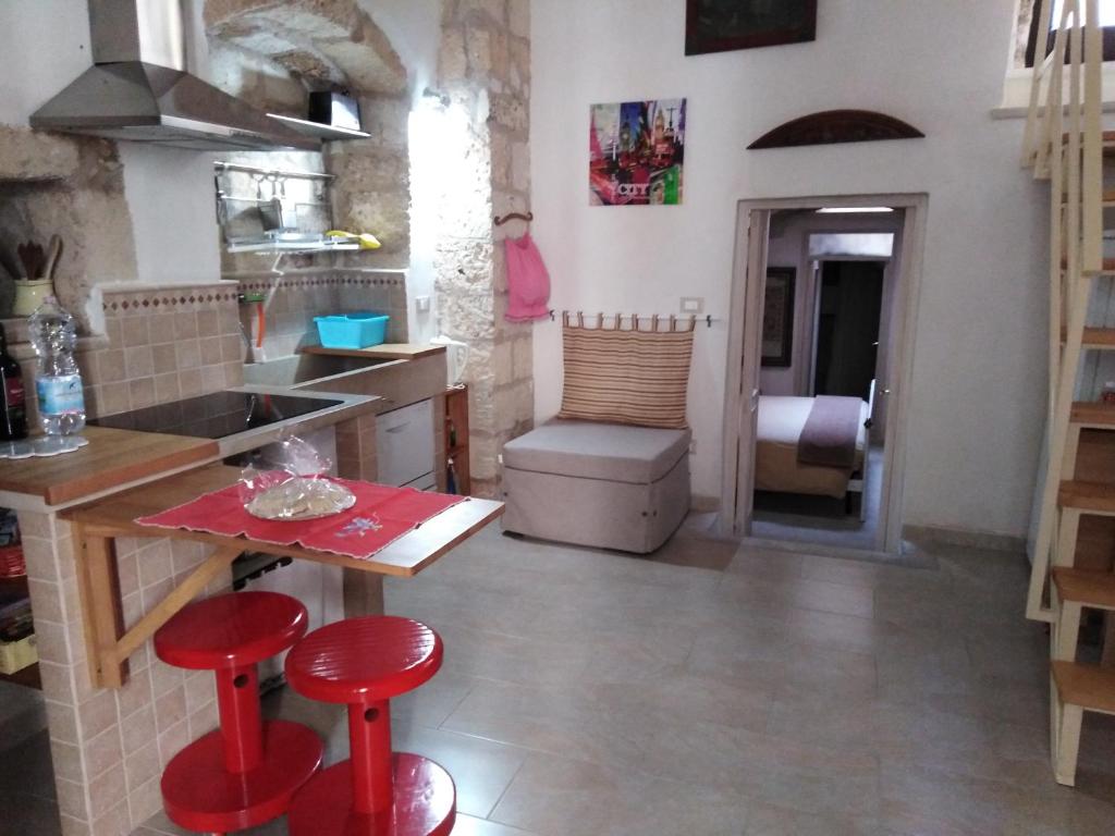 una cucina con sgabelli rossi e un tavolo in una stanza di Antico Bilocale Soleto a Soleto
