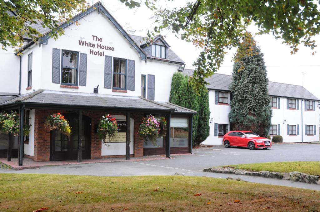 um carro vermelho estacionado em frente a um edifício branco em The White House Hotel em Telford